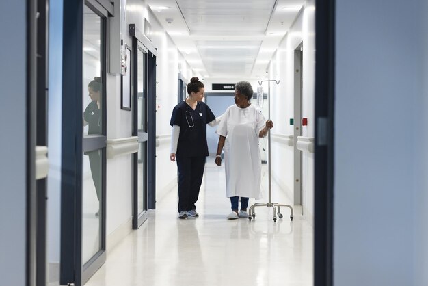 Foto eine vielfältige ärztin spricht mit einer älteren patientin mit tropfen im krankenhauskorridor