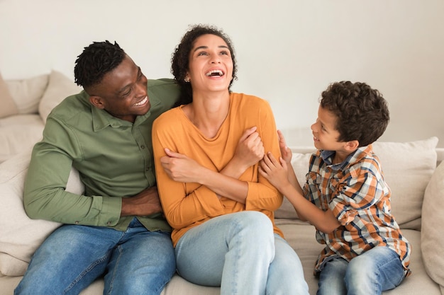 Eine vielfältige Familie, die zusammen Spaß hat und die Mutter zu Hause lachend kitzelt