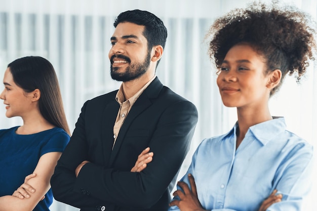 Eine vielfältige Gruppe professioneller Geschäftsleute steht in einer Reihe mit gekreuzten Armen in modernen Unternehmensbüros. Glückliche und lächelnde gemischtrassige Büroangestellte binden sich zusammen und sind gemeinsam erfolgreich