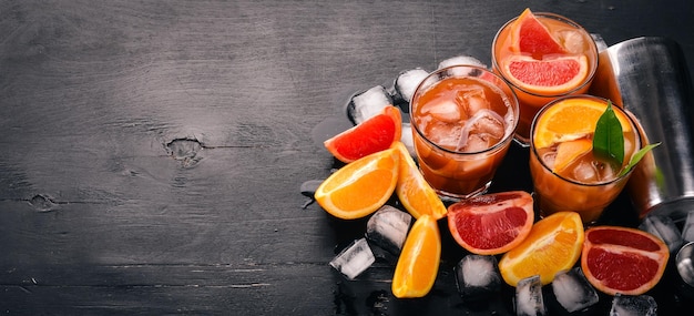 Eine Vielzahl von Cocktails aus Whiskey-Orangen- und Grapefruitsaft Negroni Auf schwarzem Holzhintergrund Draufsicht Kopierbereich