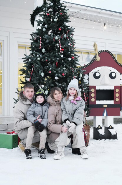 Eine vierköpfige Familie posiert im Winter vor weihnachtlicher Dekoration im Hof ihres Hauses