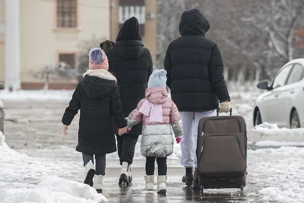 Eine vierköpfige Familie verlässt im Winter mit einem großen Koffer die Stadt für eine Reise