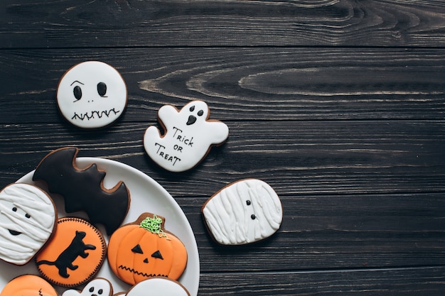 Eine Vorbereitung für Halloween. Eine Platte mit furchtsamen Lebkuchen auf einem schwarzen hölzernen Hintergrund.