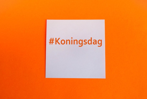 Eine Vorlage in den traditionellen Farben der Königstagsfeier in den Niederlanden Orangefarbener Hintergrund und ein weißes Papierquadrat mit dem Hashtag Koningsdag Kopierbereich