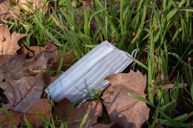 Eine weggeworfene chirurgische Maske auf einem offenen Grasfeld verwendete die Maske COVID19-Pandemie