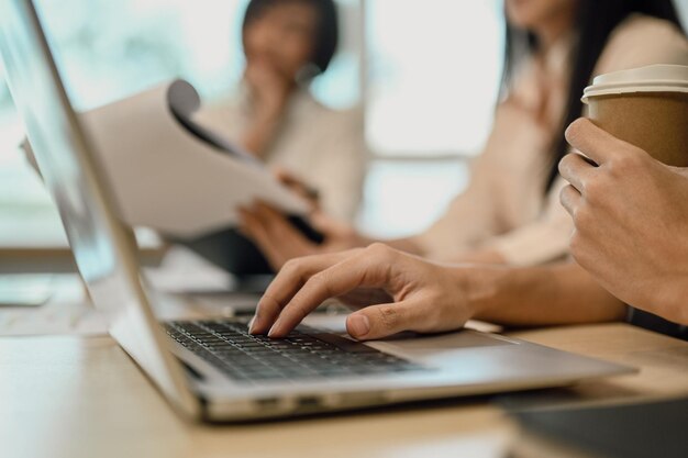 Eine weibliche Angestellte, die an einem Tagungstisch sitzt und auf einem Laptop schreibt