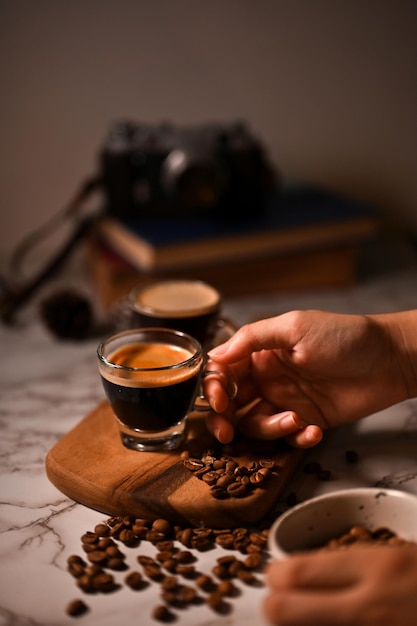 Eine weibliche Hand, die ein Glas Espresso hält, schoss Nahaufnahmebild dunkler Kaffee-Espresso-Schuss