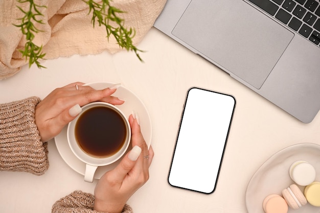 Eine weibliche Hand, die eine Tasse Kaffee in ihrem minimal schönen Schreibtisch hält