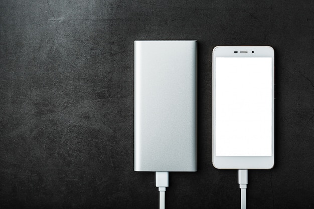 Eine weiße Powerbank lädt ein Smartphone auf. Universeller externer Akku für Geräte Freier Speicherplatz.