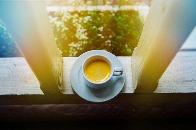 Foto eine weiße tasse auf einer untertasse morgenkaffee in der sonne auf einem glastisch der dampf des morgensofas auf der veranda des hauses