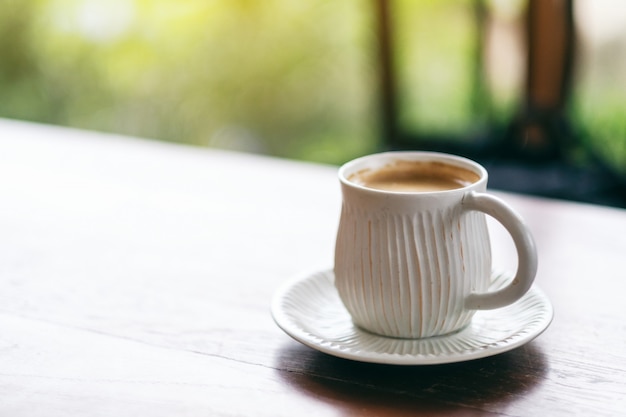 Eine weiße Tasse heißen Kaffees auf Holztisch