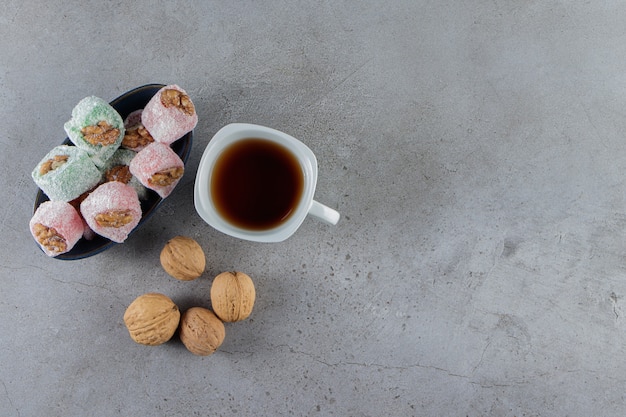 Eine weiße Tasse heißen Tee mit traditionellen türkischen Köstlichkeiten und gesunden Walnüssen