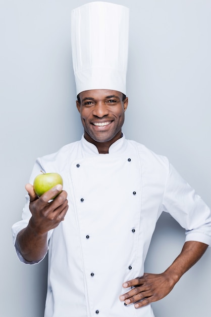 eine wichtige Zutat für Obstsalat. selbstbewusster junger afrikanischer Koch in weißer Uniform