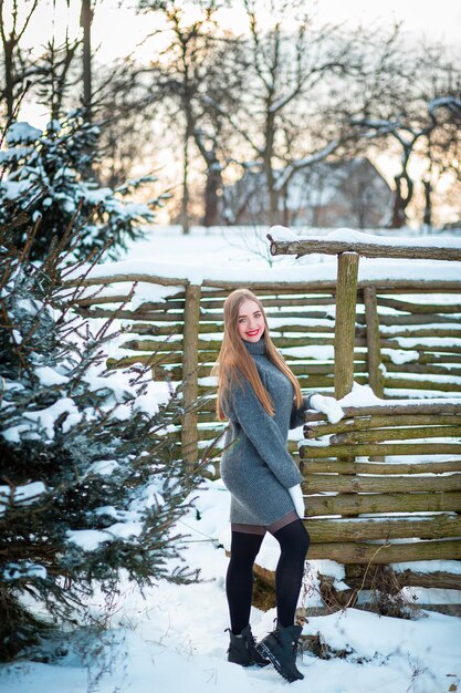 Eine Winterhütte wie in einem Märchen im Park Mädchen, das in einem Kleid im Schnee spazieren geht