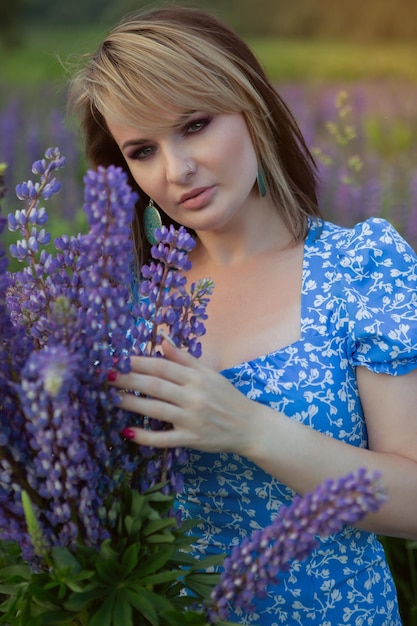 Eine wunderschöne Frau in einem langen leichten Sommerkleid und Hut auf einer Blumenwiese