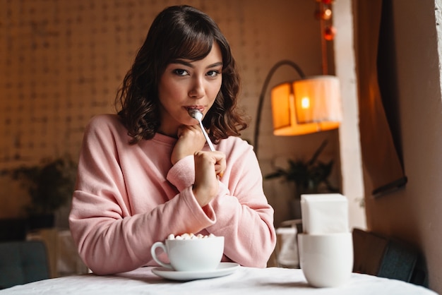 eine ziemlich erstaunliche junge Frau drinnen im Café, das Kaffee trinkt.