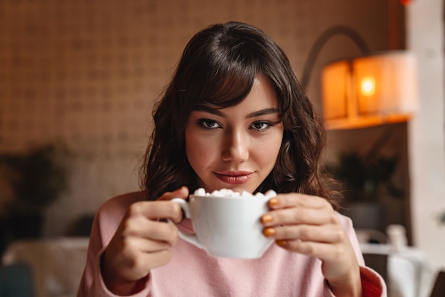 eine ziemlich erstaunliche junge Frau drinnen im Café, das Kaffee trinkt.