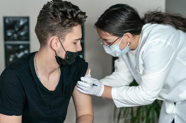 Einem jungen Mann wurde eine Spritze in die Schulter verabreicht, um sich gegen das Coronavirus impfen zu lassen