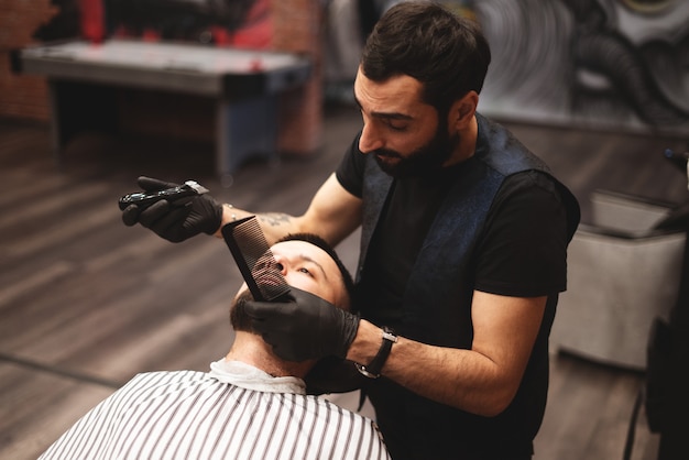 Einen Bart in einem Friseursalon mit einem gefährlichen Rasiermesser rasieren. Friseur Bartpflege. Trocknen, schneiden, Bart schneiden.