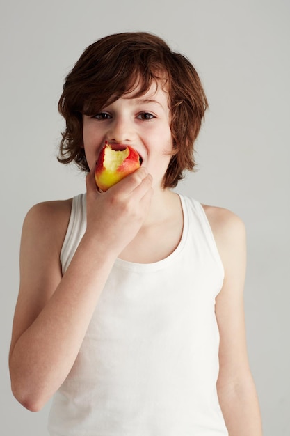 Einen Bissen nehmen Portrait eines kleinen Jungen, der einen Apfel isst