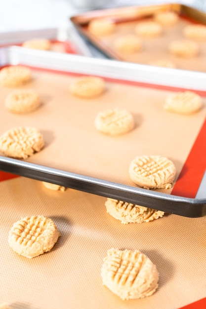 Einen Erdnussbutter-Keksteig zum Backen auf Silikonmatten legen.