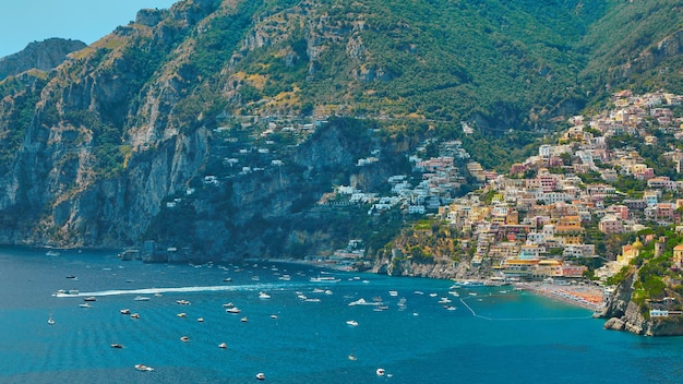 Foto einer der besten ferienorte italiens mit alten bunten villen am steilen hang, schönem strand, zahlreichen yachten und booten im hafen und mittelalterlichen türmen entlang der küste positano