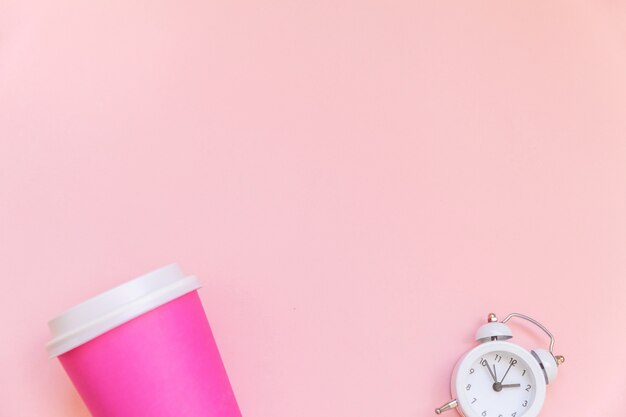 Einfach flach rosa Papierkaffeetasse und Wecker einzeln auf rosa Hintergrund legen isolated