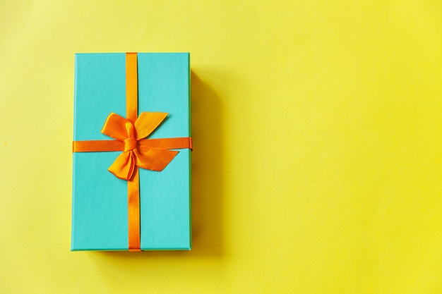 Einfache minimale blaue Geschenkbox des Designs lokalisiert auf gelbem buntem Hintergrund