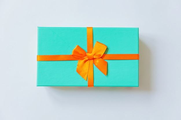 Einfache minimale Design blaue Geschenkbox mit orange Band lokalisiert auf weißem Hintergrund