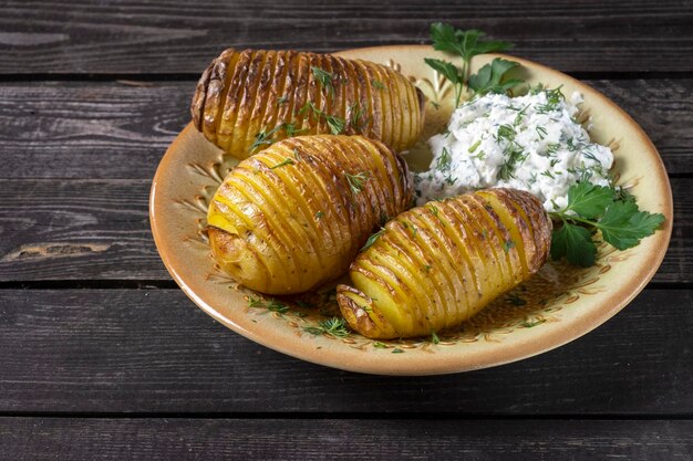 Einfache rustikale Ofenkartoffel mit Hüttenkäse und Kräutern auf dunklem Holzhintergrund