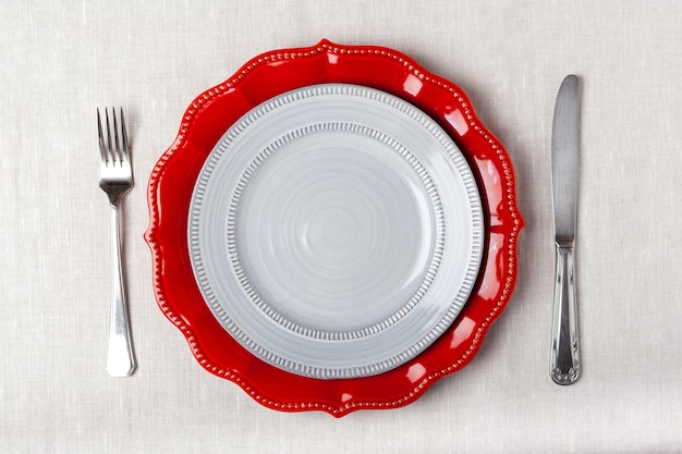 Einfache Tischdekoration von roten und grauen Platten auf einer weißen Tischdecke-Draufsicht. Foto in hoher Qualität