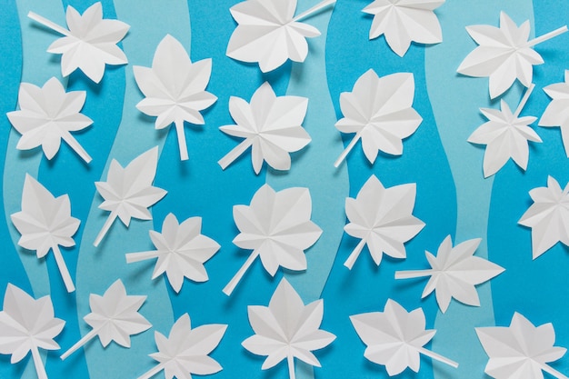 Foto einfacher hintergrund mit dekorativen elementen der herbst-winter-saison weißbuch origami gefaltete blätter auf blauem hintergrund.