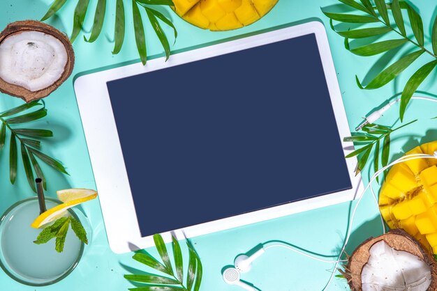 Einfacher hochfarbiger Sommerferienhintergrund Tablet mit leerem Bildschirm mit tropischen Cocktailsommerfrüchten Palmblättern auf wasserfarbenem blauem Hintergrund Reiseurlaub Flatlay Draufsicht Kopierraum