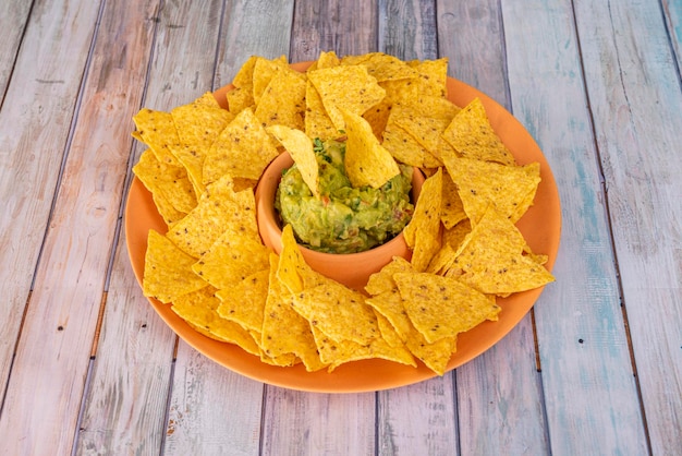 Einfacher Teller Mais-Nachos mit mexikanischer Guacamole auf einem Holztisch