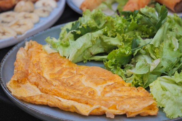 Einfaches Eieromelett serviert mit grünem Salat auf dem Tisch