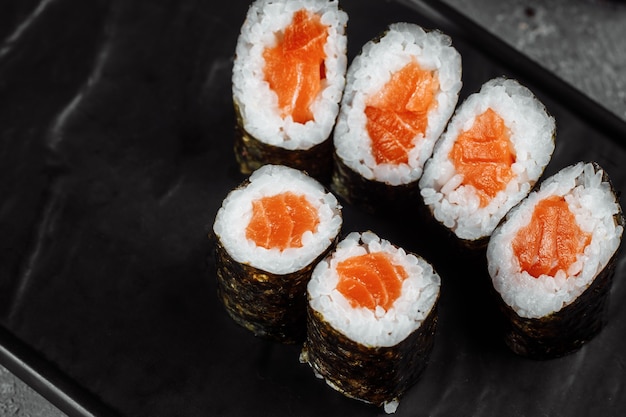 Einfaches Maki mit frischem Lachs. Sushi auf grauem Hintergrund.