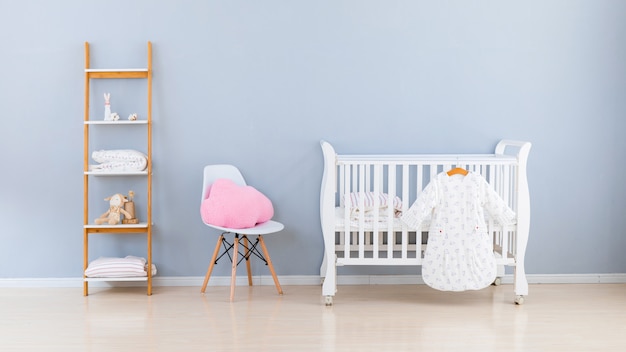 Einfaches, weißes Babyschlafzimmer mit Kinderbett und Teppich