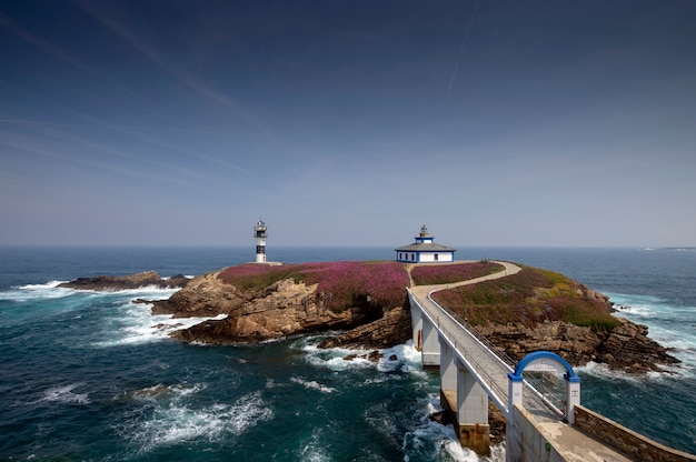 Eingangsbrücke zum Leuchtturm auf Pancha Island an einem sonnigen Tag und einer blühenden Vegetation. Ribadeo Lugo