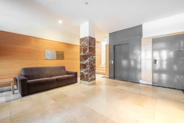 Eingangshalle eines Wohnhauses mit Marmorböden und holzgetäfelten Wänden sowie grau gestrichenen Aufzügen