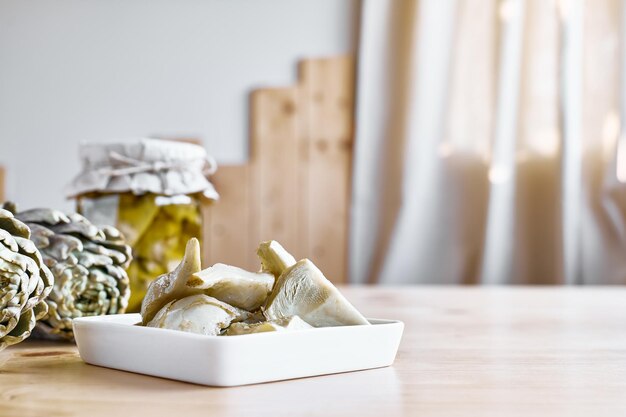 Eingelegte Artischocke mit Knoblauch in weißer Platte auf Holztisch