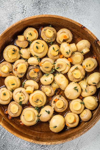 Eingelegte Champignons in einer Holzplatte. Weißer Hintergrund. Ansicht von oben.