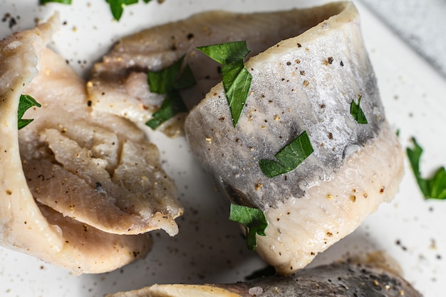 Foto eingelegter hering mit petersilie und roter zwiebel. grauer hintergrund. ansicht von oben