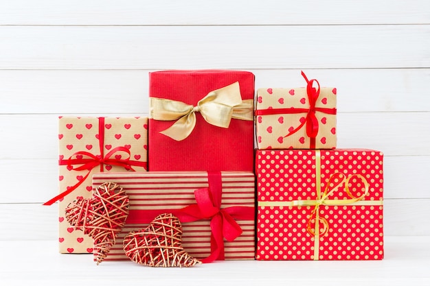 Eingewickelte Geschenkkästen und zwei rote Herzen auf weißem hölzernem Hintergrund. Platz kopieren