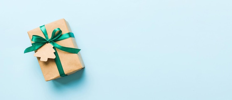 Foto eingewickeltes weihnachts- oder anderes handgefertigtes weihnachtengeschenk in papier mit farbigem band geschenkboxdekoration des geschenks auf farbenfroher tischoberfläche mit kopierplatz