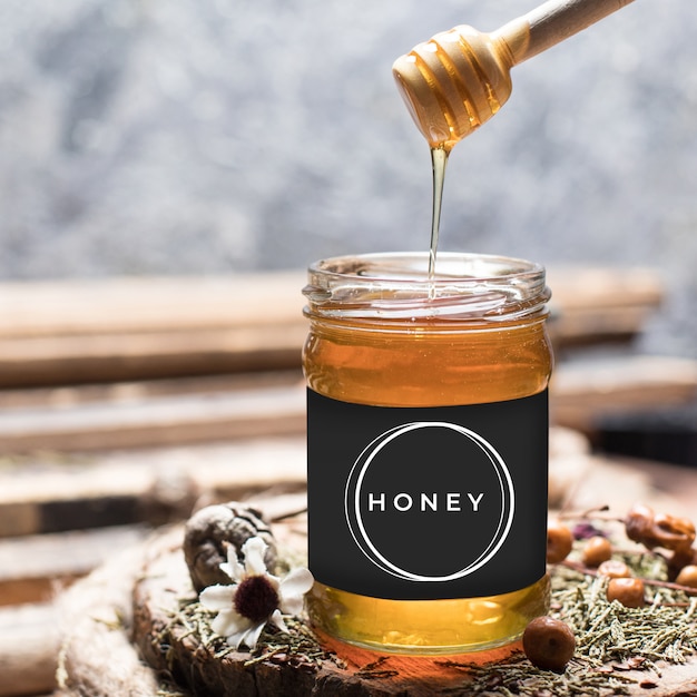 Eingießen von aromatischem Honig in ein Glas, süßer Honig tropft vom Löffel in ein Glas
