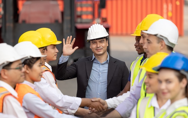 Einheits- und Erfolgskonzept. Untere Ansicht der Leute des Ingenieurteams, die Hände halten, die am Containerhof zusammenhalten.