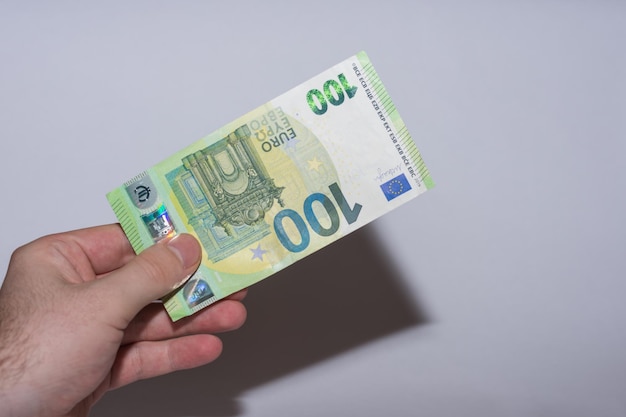 Einhundert-Euro-Banknoten, die in einer Hand gehalten wurden, Inflation auf dem Markt mit grauem Hintergrund xA