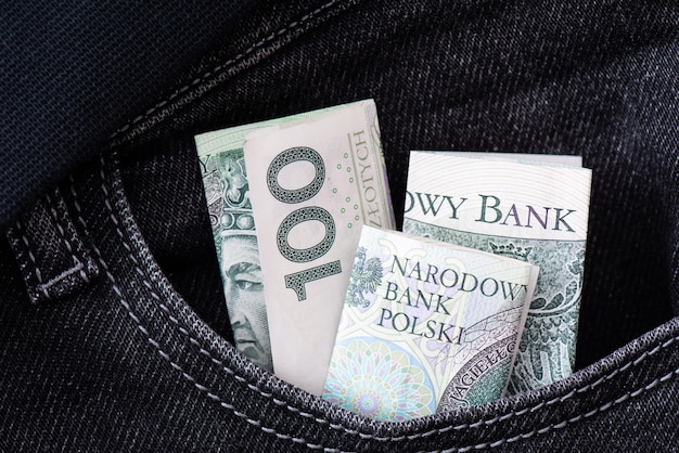 Einhundert Zloty-Papierbanknoten in der Tasche der schwarzen Jeans Sparen beim Speichern und Umtauschen von Geld Geschäftshintergrund