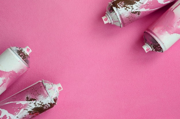 Einige gebrauchte pinkfarbene Spraydosen mit Farbtropfen liegen auf einer Decke