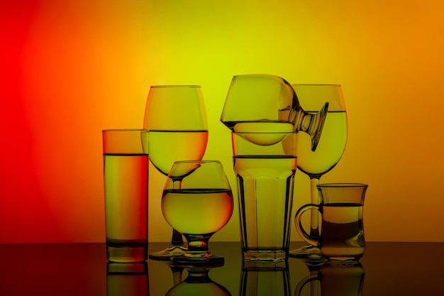 Einige Gläser für verschiedene Getränke auf buntem Hintergrund gestapelt